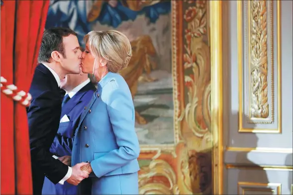  ?? PHILIPPE WOJAZER / REUTERS ?? French President Emmanuel Macron kisses his wife Brigitte Trogneux during the handover ceremony in Paris.