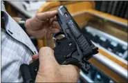 ?? BRITTAINY NEWMAN/THE ASSOCIATED PRESS, FILE ?? A customer checks out a hand gun that is for sale and on display at SP firearms on June 23, 2022, in Hempstead, N.Y.