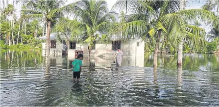  ?? AP ?? A woman and a child wade through knee-deep water
to reach their home during a king
tide on Kili in the Marshall Islands in
January.
