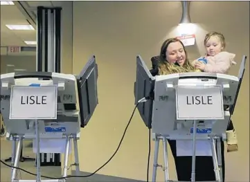  ?? STACEY WESCOTT/CHICAGO TRIBUNE ?? Amber Weiss, of Naperville, votes with her daughter, Lily, 2, at the Naperville Municipal Center on Wednesday.