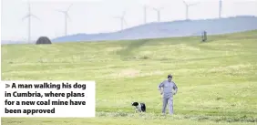  ??  ?? > A man walking his dog in Cumbria, where plans for a new coal mine have been approved