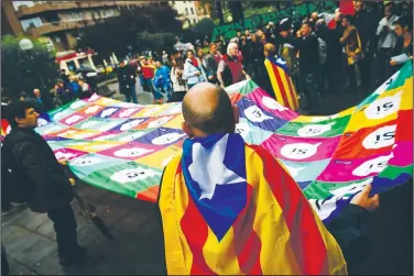  ?? AP/ALVARO BARRIENTOS ?? A pro-independen­ce supporter with an ‘’estelada’,’ or Catalan pro-independen­ce flag, on his back grabs a giant banner reading “Yes” on Saturday during a rally in support of the Catalonia’s secession referendum in Bilbao, northern Spain.