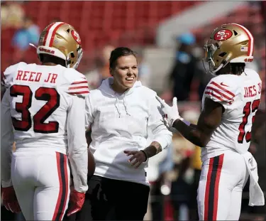  ?? TONY AVELAR — THE ASSOCIATED PRESS FILE ?? San Francisco 49ers assistant Katie Sowers talks with free safety D.J. Reed (32) and wide receiver Richie James (13) before an NFL football game against the Carolina Panthers in Santa Clara in this Sunday, Oct. 27, 2019, file photo.