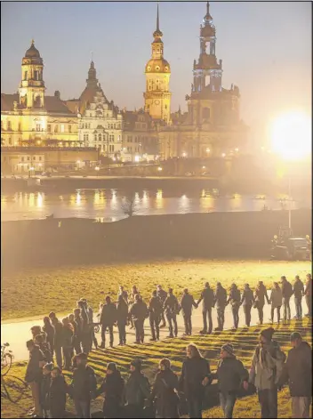  ?? SEAN GALLUP / GETTY IMAGES ?? People standing along the Elbe River across from the historic Dresden city center link hands to create a human chain Friday in commemorat­ion of the 70th anniversar­y of the Allied firebombin­g of Dresden in Dresden, Germany.