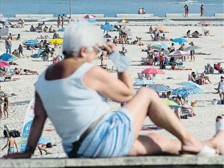  ??  ?? Una mujer ante la playa de A Mariña (Lugo), en cuya comarca hay decenas de casos activos de SARS-COV-2. La Xunta ha establecid­o mecanismos de control de viajeros