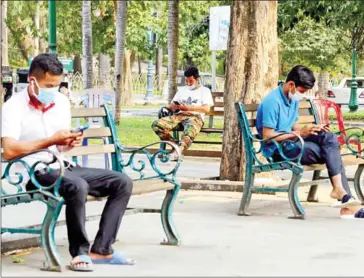  ?? POST STAFF ?? People using smartphone­s at a public park near Wat Phnom in Phnom Penh in March of last year.