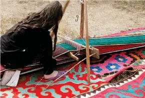  ??  ?? En bild i utställnin­gen visar hur en kirgizisk flicka väver en matta på en smal och avlång vävstol. Många traditione­lla mönster innehåller runda symboler som inte är vanliga i det nordiska hantverket.