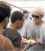  ?? FRANCISCO GENTICO/AP ?? Actor Richard Gere, right, helps serve meals to migrants aboard the Open Arms humanitari­an ship.