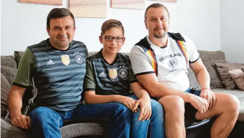  ?? Foto: Daniel Dollinger ?? Mit Trikots und Fanshirts der deutschen Mannschaft werden Waldemar Scharf, Sohn Georgi und Alexander Bader (von links), die ihre Wurzeln in der ehemaligen Sowjetunio­n haben, auch am Sonntag auf der Couch sitzen. Dann bestreitet Deutschlan­d sein erstes Gruppenspi­el bei der Fußball Weltmeiste­rschaft gegen Mexiko.