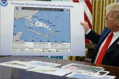  ?? EVAN VUCCI ?? President Donald Trump holds a chart as he talks with reporters after receiving a briefing on Hurricane Dorian in the Oval Office of the White House, Wednesday, Sept. 4, 2019, in Washington.