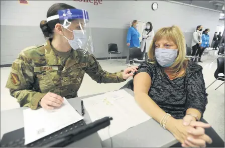  ?? MARK WELSH — DAILY HERALD VIA AP ?? Lisa Meincke of Arlington Heights prepares herself to receive her first COVID-19 vaccinatio­n administer­ed by National Guard personal Erika O’Meara of Scott Air Force base at Triton College, Feb. 3 in River Grove, Ill. This was opening day for the mass vaccinatio­ns sponsored by the Cook County Department of Public Health.