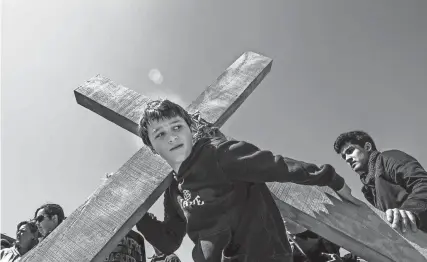  ?? THE COMMERCIAL APPEAL FILES ?? March 25, 2016: John Goodwin, 10, lifts a wooden cross as he readies to carry it to St. Patrick's Catholic Church, 277 S. Fourth, during the Stations of the Cross neighborho­od event on Good Friday.