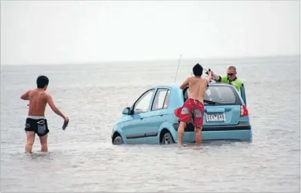  ?? Photo: REUTERS ?? Wrong turn: Tourists retrieve some of their valuables from a rental car stranded in the ocean at Oyster Point, about 25km east of Brisbane, after being misled by a GPS system.