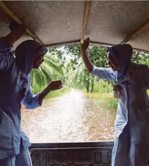  ??  ?? Sarina Hashim (right) and Noorhidaya­h Abd Halim travelling in a four-wheel-drive to Kampung Permatang Siput, Pekan, yesterday.