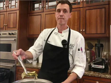  ?? JANET PODOLAK — THE NEWS-HERALD ?? Chef Brian Toomey scoops up cucumbers on their way to becoming pickles during a cooking class he is leading at a Taste of ICASI open house in Chester Township.