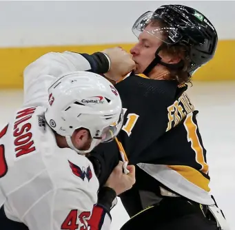  ?? Stuart caHill pHotoS / Herald Staff ?? BRINGING IT: Capitals right wing Tom Wilson connects with Bruins center Trent Frederic during a third-period fight at TD Garden on Friday night. At left, Bruins defenseman Jarred Tinordi and Wilson exchange blows.