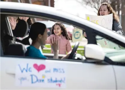  ?? ASHLEE REZIN GARCIA/ SUN- TIMES ?? With the school building closed amid the coronaviru­s pandemic, John C. Dore Elementary School teachers and staff drive around the neighborho­od in a caravan of cars waving to students and families on the Southwest Side in early April.