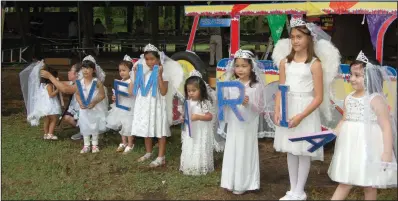  ??  ?? Young “angels” hold letters spelling “Ave Maria” as they await the start of the Santacruza­n Parade.