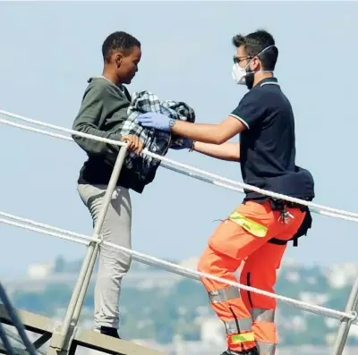  ??  ?? In salvo Un volontario aiuta una migrante con un bimbo in braccio a scendere dalla nave britannica «Echo» al porto di Bari (Fotogramma)