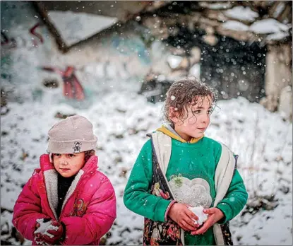  ?? MUHAMMED SAID / ANADOLU AGENCY ?? Children play in snow on March 13 in Jabal ez-Zawiya district, Idlib, Syria. About three-quarters of Idib’s population reportedly relies on regular humanitari­an assistance because of damaged infrastruc­ture and economic hardship.