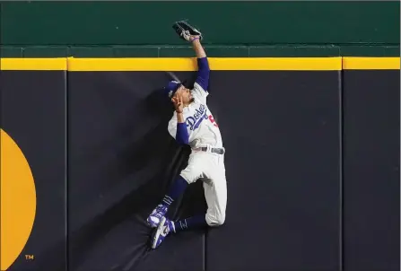  ?? The Associated Press ?? L.A. Dodgers right-fielder Mookie Betts makes a catch and robs Atlanta Braves’ Freddie Freeman of a home run during the fifth inning in Game 7 of their National League Championsh­ip Series, Sunday, in Arlington, Texas.