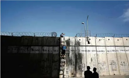  ?? Nasser Shiyoukhi - 9.jun.17/Associated Press ?? Palestinos escalam muro na Cisjordâni­a para irem a oração em Jerusalém; Brasil só mediará conflito se for convidado