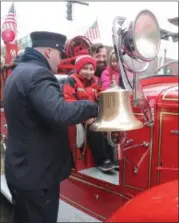  ?? BY LAUREN HALLIGAN LHALLIGAN@DIGITALFIR­STMEDIA.COM ?? A fireman shows a young event-goer how to ring the antique firetruck’s bell at the annual Victorian Stroll in downtown Troy.