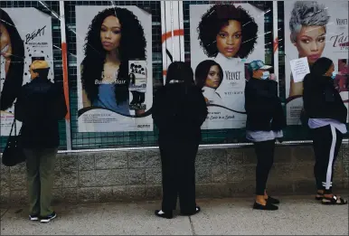  ?? SHANNON STAPLETON — REUTERS ?? People wear face masks as they wait outside a beauty salon in the Highland Park section of Detroit. Multinatio­nal companies in recent years have snapped up products aimed at Black consumers and marketed those brands as authentica­lly Black.