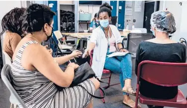  ?? VIRGINIE NGUYEN/THE NEW YORK TIMES ?? A health care worker, center, assists people with medical documents before they receive a COVID-19 vaccine June 16 in Brussels. The European Union is now in the fortunate position of not struggling for supply.
