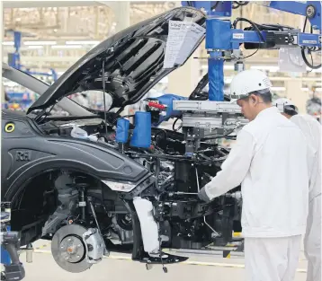  ?? PATTANAPON­G HIRUNARD ?? Mechanics check a car’s engine at a Honda assembly plant in Prachin Buri.