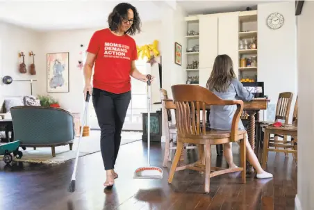  ?? Photos by Jessica Christian / The Chronicle ?? San Mateo City Councilwom­an Amourence Lee sweeps up the kitchen while daughter Mia Lin participat­es in an online art class.