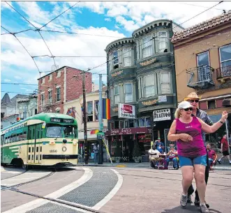  ?? JUSTIN FRANZ/WASHINGTON POST ?? A streetcar painted in vintage green and cream livery passes people square dancing in the famous Castro District of San Francisco.