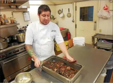  ?? VIRGINIA LINDAK — FOR DIGITAL FIRST MEDIA ?? Chef Seth Williams takes the main course out of the oven at the annual Camphill Village Kimberton Hills “What’s For Dinner?” fundraiser. A second dinner will be held in January to support the village’s programs.