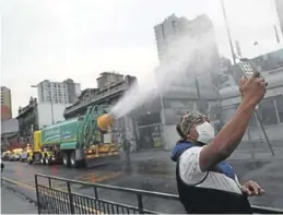  ?? REUTERS / IVÁN ALVARADO ?? Un hombre se hace un selfie durante la desinfecci­ón de calles.