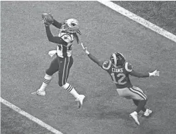  ??  ?? Patriots cornerback Stephon Gilmore intercepts a pass intended for Rams wide receiver Brandin Cooks in the fourth quarter.