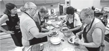  ?? SARAH KLOEPPING/USA TODAY NETWORKWIS­CONSIN ?? Gina Guth, owner of The Flour Pot (pictured second from left), instructs cooking class participan­ts how to make Belgian pies using fillings such as cherry and apple on June 26 in De Pere.