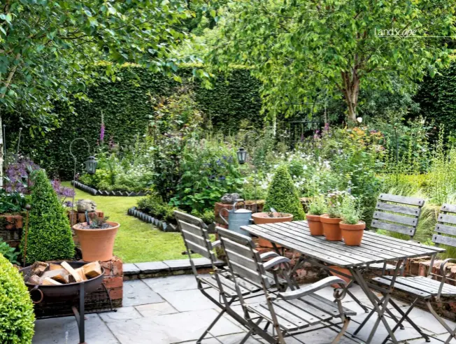  ??  ?? A small paved courtyard, with dining table and chairs nestled to one side, flanked by a tall hornbeam and silver birches, provides a peaceful place to sit or dine as the weather grows warmer and the days stretch out.