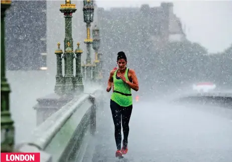  ??  ?? Rain, rain go away: A determined jogger gets drenched as she runs across Westminste­r Bridge yesterday LONDON