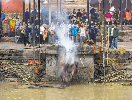  ?? ?? Top: A man pushes cremated remains into the Bagmati River at the Pashupatin­ath Temple in Kathmandu.