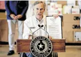  ?? Nick Wagner / Associated Press ?? Gov. Greg Abbott shows an executive order regarding reporting data about the coronaviru­s during a news conference Tuesday.