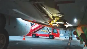  ?? Courtesy: Air India ?? A worker (right) inspects the damaged undercarri­age of the Boeing 737-800 in Mumbai yesterday. The Air India Express flight had 130 passengers and six crew on board.