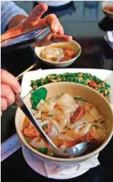  ??  ?? Andrew Zimmern snaps a cell phone photo of his order of Taiwanese noodle soup and minced vegetables at Happy Stony Noodle in Elmhurst, Queens in New York.