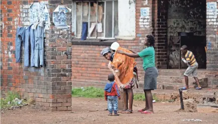  ??  ?? A woman helps a neighbor with her baby in the low-income neighborho­od of Mbare in Harare, Zimbabwe, on Thursday. BEN CURTIS/AP