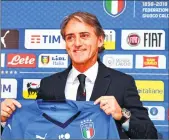  ??  ?? Italy's national football team newly appointed head coach, Roberto Mancini holds Italy's jersey during a press conference on Tuesday at the national team's training centre at Coverciano near Florence.