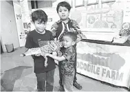  ?? ?? TARIKAN: Tiga pengunjung kanak-kanak memegang sendiri anak buaya hidup yang dipamerkan pada karnival ulang tahun ke-25 Petrosains di PlaySmart Centre Kuching.