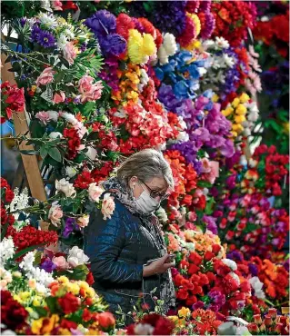  ?? AP ?? A flower seller wearing a face mask waits for customers at a market in Minsk. Belarus remains open despite coronaviru­s shutdowns elsewhere.