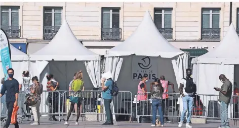  ?? FOTO: DPA ?? Menschen mit Gesichtsma­sken stehen Schlange in Paris, um sich an einem Stand vor dem Rathaus kostenlos auf das Coronaviru­s testen zu lassen.
