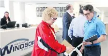  ??  ?? One of the first customers, Jackie Rivard, centre, is assisted by Trevor Bennet, the city’s manager of business process modernizat­ion.