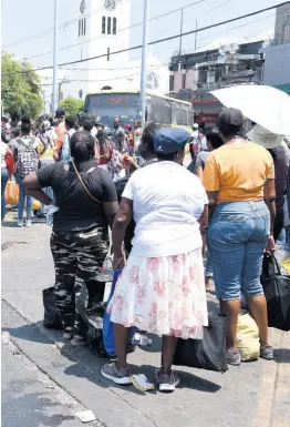  ??  ?? Scores of residents in downtown Kingston waiting on transporta­tion to get home.