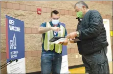  ?? STEVE MARCUS ?? Bobby Donnell, an environmen­tal health specialist with the Southern Nevada Health District, checks the ID of Victor Rodriguez Jan. 29 at a COVID-19 “pop up” vaccinatio­n clinic at Jerome Mack Middle School in Las Vegas’ east valley. The school is situated in the 89121 ZIP code, where according to U.S. Census data, 43% of the population is Latino.